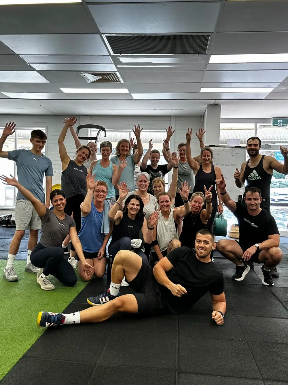 Group of Tribe Wellness Co members in the gym, smiling and raising their hands