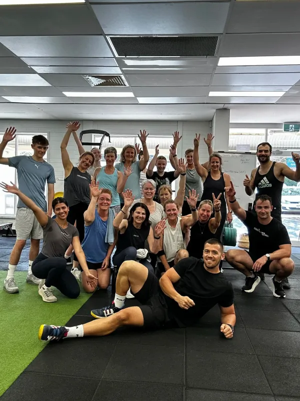 Group of people in a gym, smiling and raising their hands