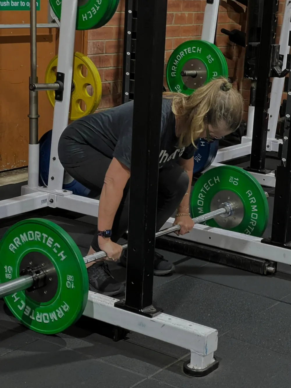 A woman lifting a barbell with green weight plates