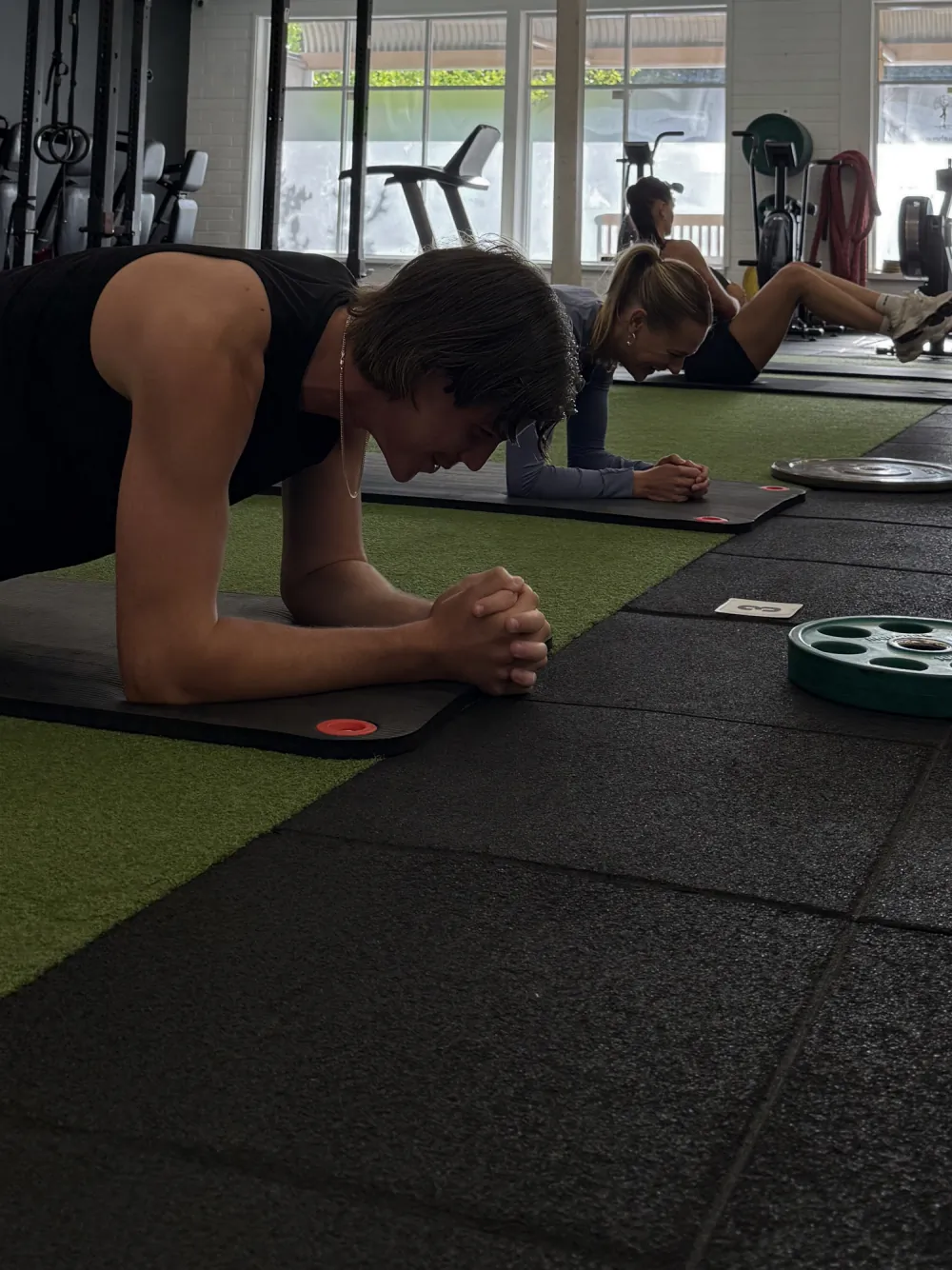 Three people performing plank exercises on mats