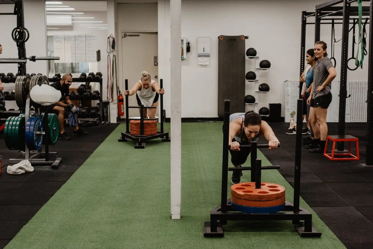 Members pushing weighted sleds during a small group training session