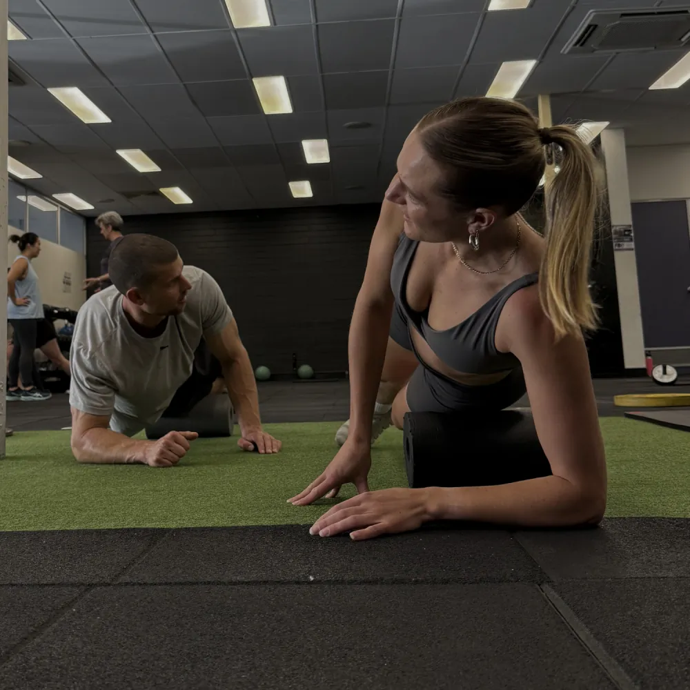 A coach guiding a member through a plank during a one on one session